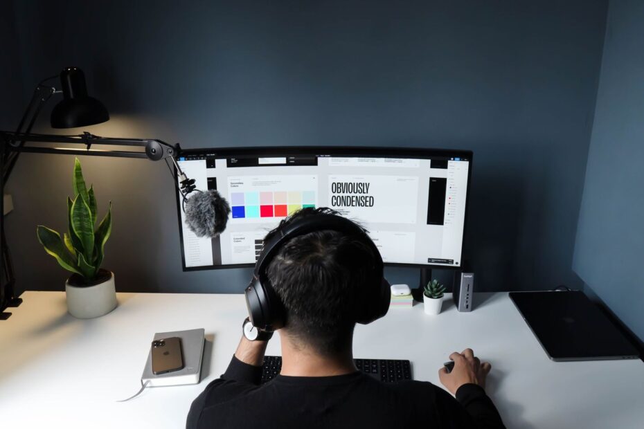 A man using a computer in a stylish home office with a minimalist setup.